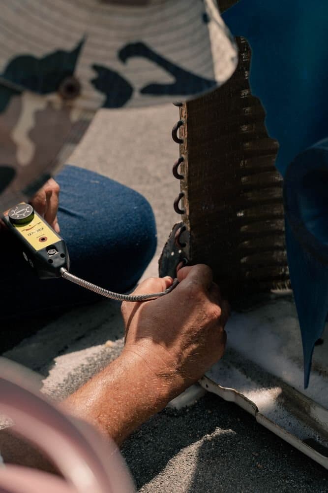 HVAC technician inspecting an air conditioning coil with a diagnostic tool